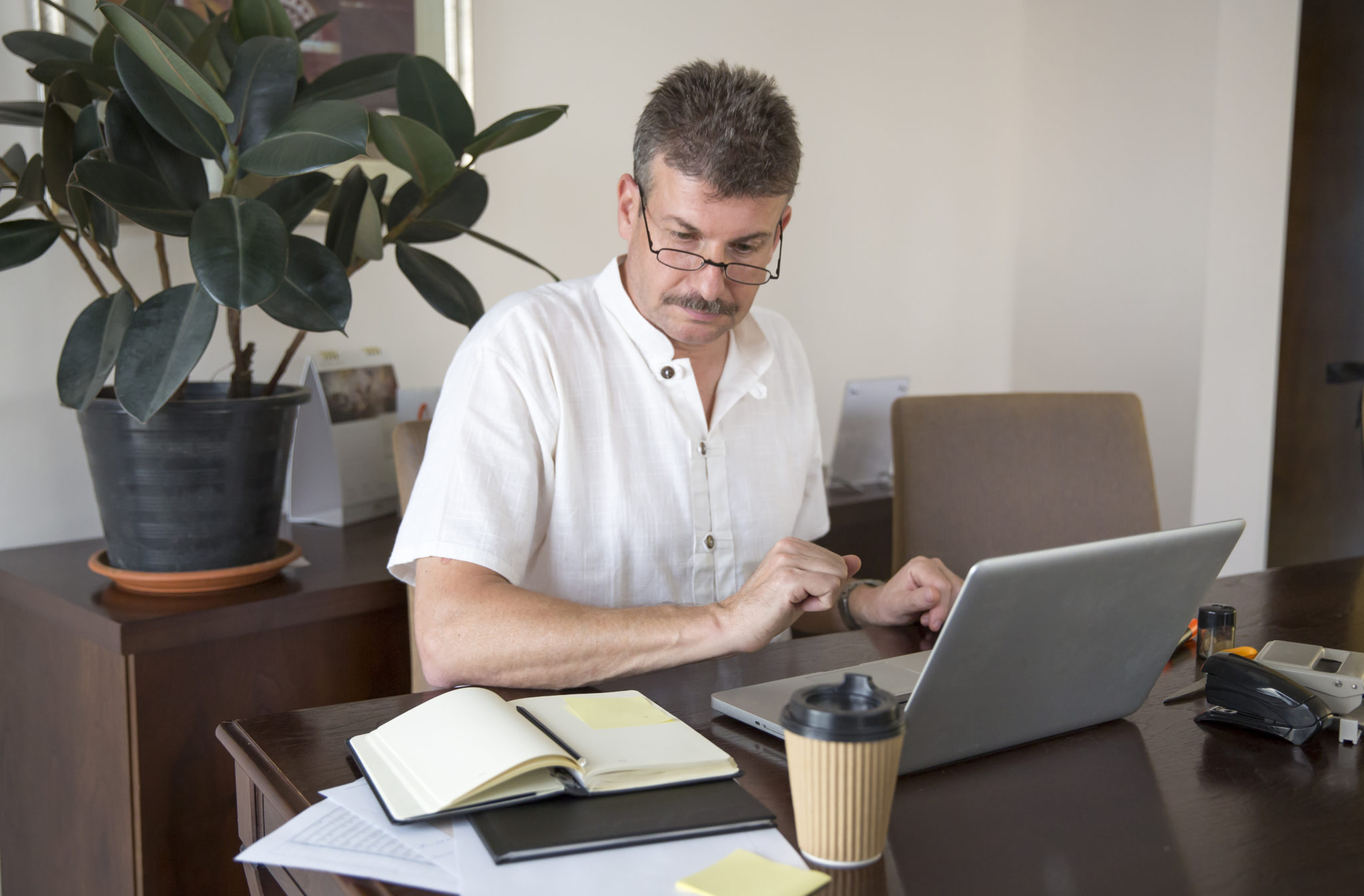 家のオフィスでパソコンを使って働く中年男性